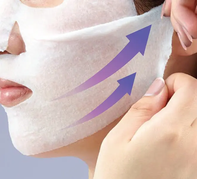 ストレッチシートマスクをこめかみから引き上げるように貼り付けている女性